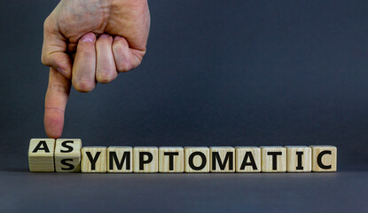 Asymptomatic or symptomatic covid-19. Male hand turns cubes and changes the word 'symptomatic' to 'asymptomatic'. Beautiful grey background. Medical and covid-19 pandemic concept. Copy space.