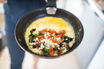 Mushroom, tomato and cheese omelette on a frying pan