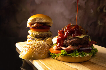 Two hamburgers, putting katchup on two double gourmet hamburgers, cheese, tomato, bacon, lettuce,...