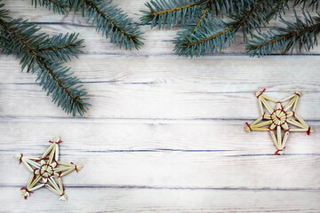 branches of a blue spruce with Christmas decorations on a light wooden background