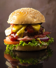 Burger, gourmet double burger, cheese, tomato, lettuce, onion. on reflective black surface, abstract background, selective focus.