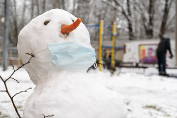 snowman in a protective mask in the snow