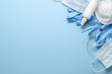 Used disposable medical face masks, latex gloves, syringes, test tubes on pastel blue background....