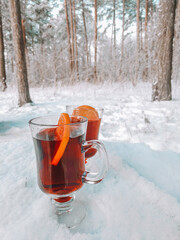 two glasses of mulled wine stand on a stump outside in winter