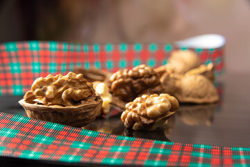 Nuts, details of nuts scattered with Christmas ribbons on a reflective black surface, abstract background, selective focus.