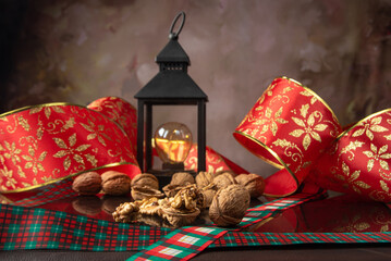Nuts, details of nuts scattered with Christmas ribbons and lantern on a reflective black surface,...