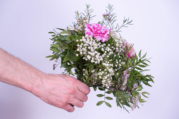 a man's hand stretches forward a bouquet of festive flowers