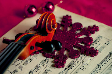 Viola head resting on top of a red snow flake decoration, on top of a music sheet 