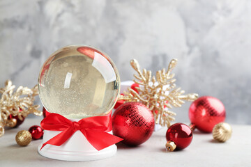 Beautiful snow globe and Christmas balls on light table. Space for text