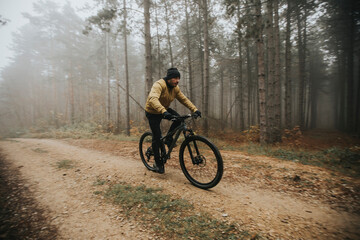 Young man biking through autumn forest