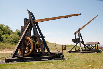 Ancient throwing machines. Throwing machines in the clearing. Wooden historical stone throwing machines.