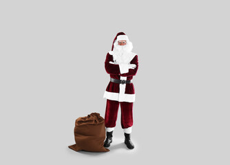 Full length portrait of Santa Claus with sack on light grey background