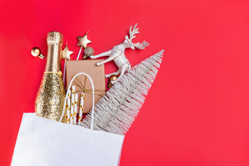 Christmas decor and gifts in paper bag on red background.