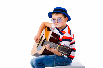 A boy kid plays guitar on a white studio background