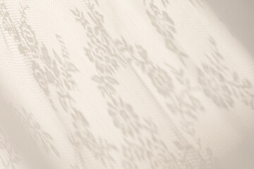 Sunlight on the wall with shadows from the white lace curtain. Spring and summer texture background