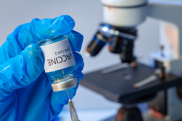 Doctor hands in blue gloves holding Sars-cov-2 vaccine vial