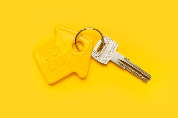 House symbol and metal keys on yellow background flat lay top view copy space. House door keys. Concept of buying home, apartment. Renting a house, real estate. Mortgage, credit, real estate insurance
