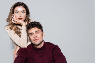  young couple in turtleneck jumpers posing isolated on grey