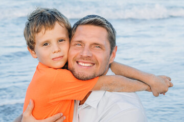 Fototapeta na wymiar Father and son playing on the beach together. Portrait of a cheerful and happy family. Friendly family concept. 