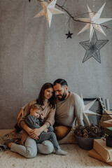 Naklejka premium Young family with a cute boy spend intimate moments in the holiday decor at home.
