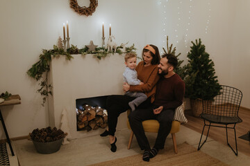 Obraz premium Merry Christmas and Happy Holidays! Pretty family spend good time together in front of the fireplace.