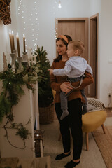 Merry Christmas and Happy Holidays! Pretty young woman spend good time together with her little boy in front of the fireplace.