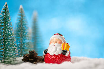 Winter background with Christmas trees and toy Santa Claus on a snow.