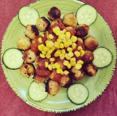 fried dumplings with corn, tomato paste and cucumbers on a wide round green plate