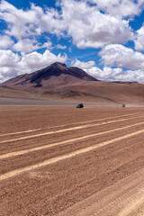 Two cars driving through the southwest of the altiplano in Bolivia in a cloudy day