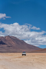 A car driving through the southwest of the altiplano in Bolivia in a cloudy day