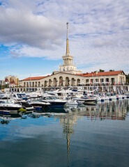 Fototapeta premium Sochi, Russia - November 23, 2020: Sochi, Russia - November 23, 2020: Sochi Commercial Sea Port. Main building of Marine Station. Motor ships and yachts on marinas. Close-up. Calm Black Sea.