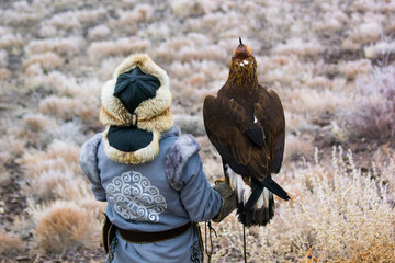 a hunter with an eagle is waiting for prey on a hill