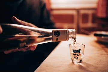 Serbia, Belgrade, November 2020 Pouring rakija, Serbian drink to a small glass
