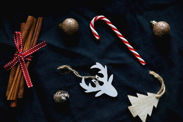 Various Christmas ornaments and cinnamon sticks on dark blue background. Flat lay.