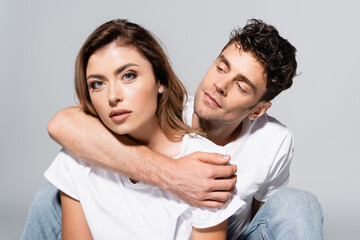  couple in white t-shirts embracing isolated on grey