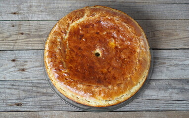 Round pie with filling on wooden background. Food background.