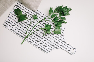 Top view of fresh parsley on cutting board. Fresh greens on white table. copy space. Mock up for blog or recipe, flat lay