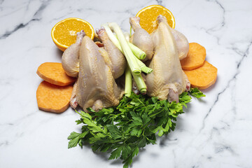 Whole coquelet chickens with raw vegetables ready to cook