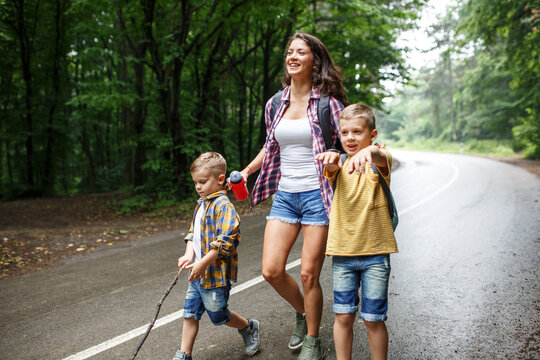 Mother and her little sons hiking by the rural country road.Outdoor spring leisure concept.	
