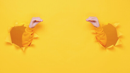 Woman fun arms showing talking to each other hands open shut mouth isolated through torn yellow wall background studio. Copy space advertisement place for text image Advertising area workspace mockup