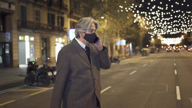 Businessman with face mask crossing city avenue with Christmas decoration