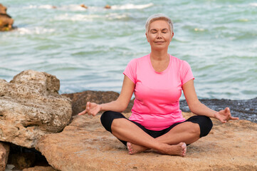 Fototapeta na wymiar Sports mature woman at the beach make meditate exercises