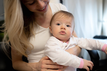 young caucasian mother with her baby sitting on her knees and clapping hands