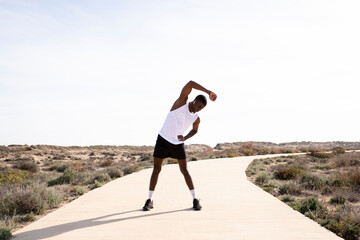 Young black sports trainer doing stretching and warm-ups before training. Concept of health.