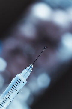 Syringe with needle up and jet and drops of medicine close up
