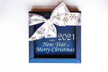 Blue shiny box with a white bow. festive packaging. Christmas decorations on white background with text. Holiday and celebration. Flat lay, top view