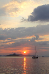 Alone sailboat at sunset. Atmospheric seascape with orange sun.