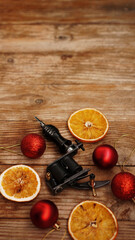 Tattoo machines on a christmas background - christmas decor with red balls and dried oranges on a...
