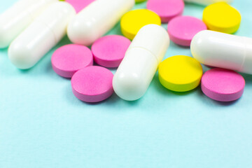 Colored pills and tablets on green background. Close up. Medical treatment concept.