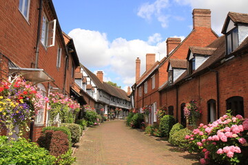 Fototapeta na wymiar Brick and Half Timbered Houses in Shakespeare's Country Malt Mill Lane Alcester Warwickshire, UK. With hanging baskets & floral blooms in High Summer.